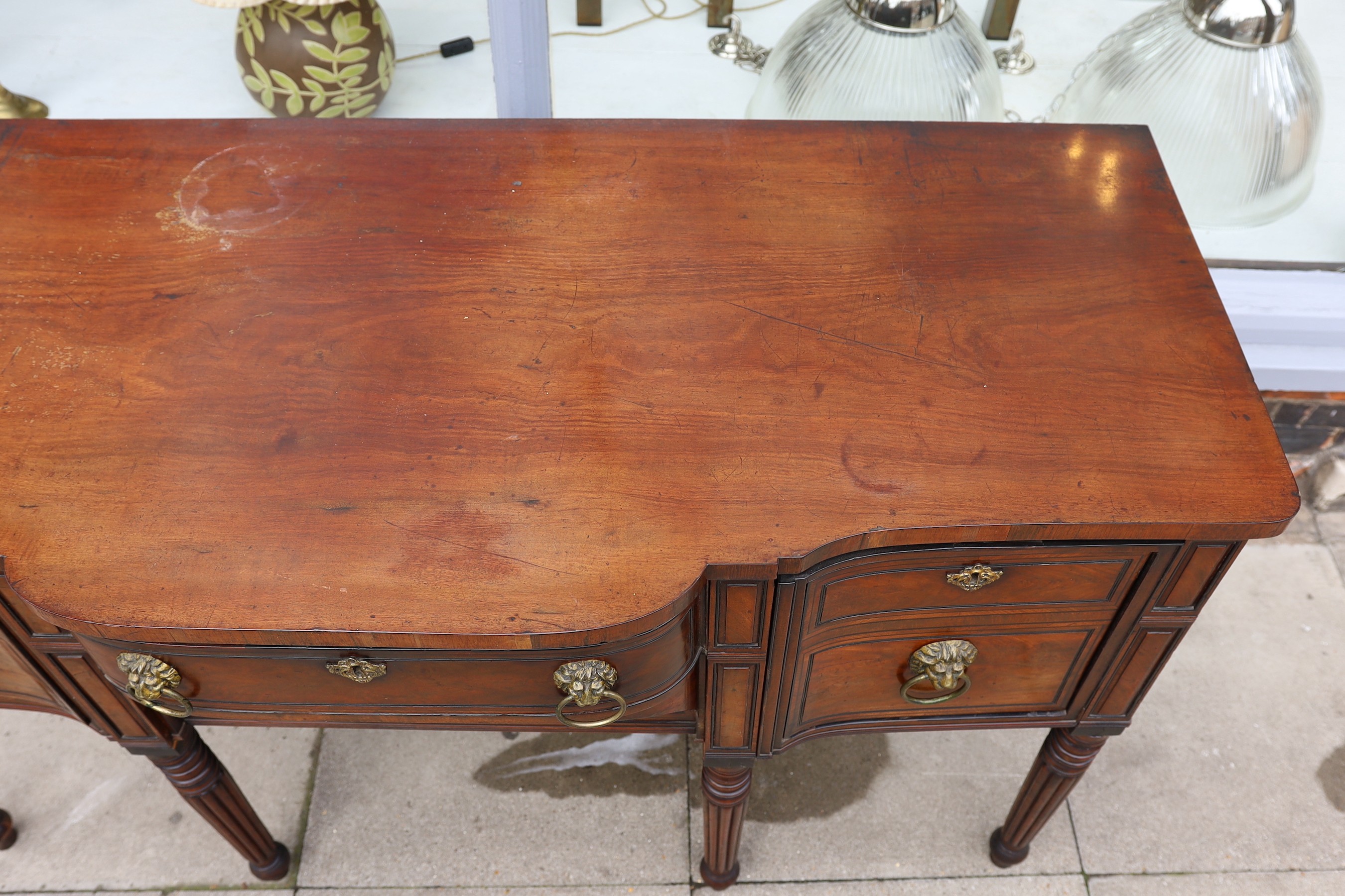 A Regency ebony strung mahogany breakfront sideboard, each deep drawer with ‘secret’ revolving cellaret compartment, centred with two long drawers, on ring turned fluted and tapered legs, width 167cm. depth 69cm. height